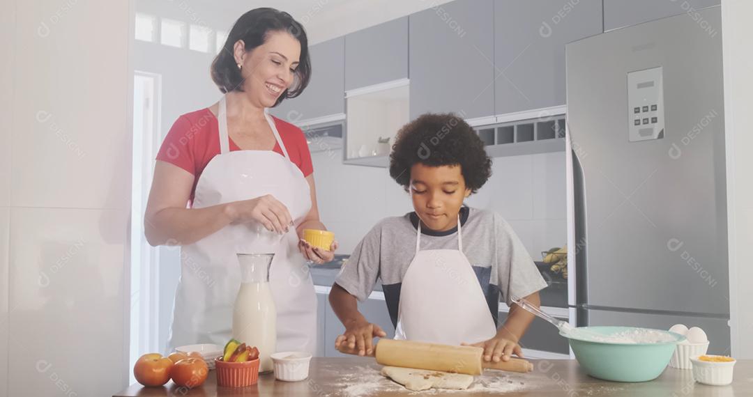 Família jovem cozinhar comida na cozinha. Menina feliz com a mãe misturando a massa. Mãe e filho preparando a massa