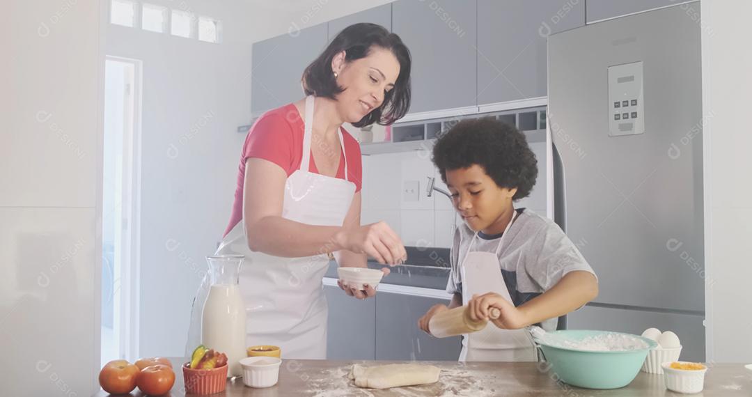 Família jovem cozinhar comida na cozinha. Menina feliz com a mãe misturando a massa. Mãe e filho preparando a massa
