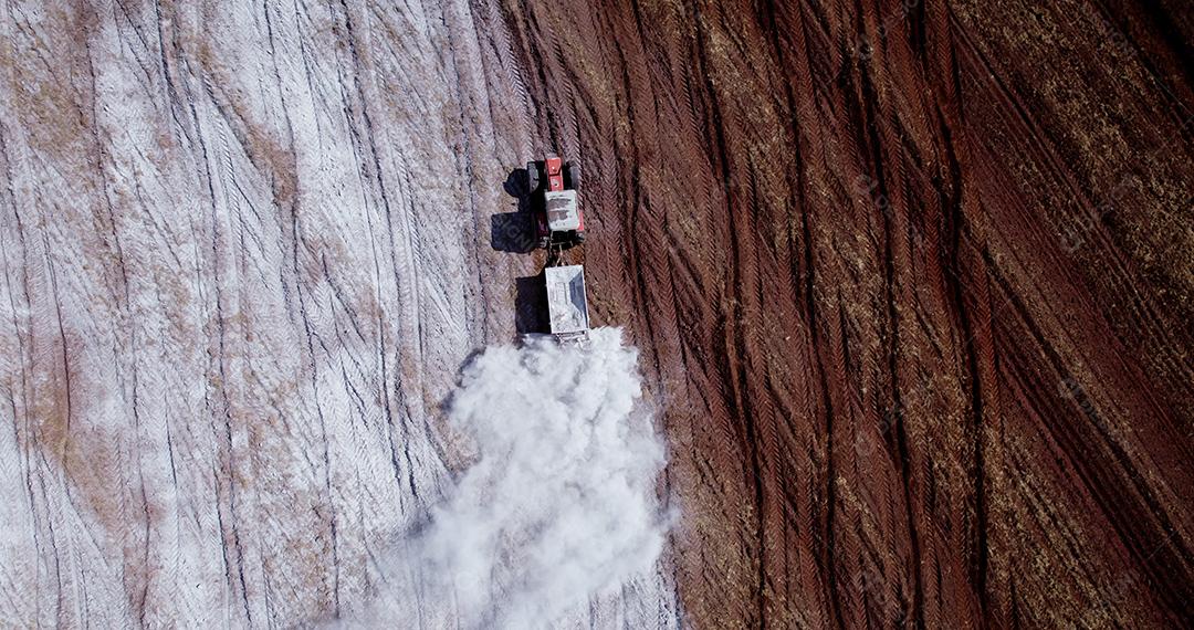 Trator aplicando calcário ao solo para corrigir a acidez