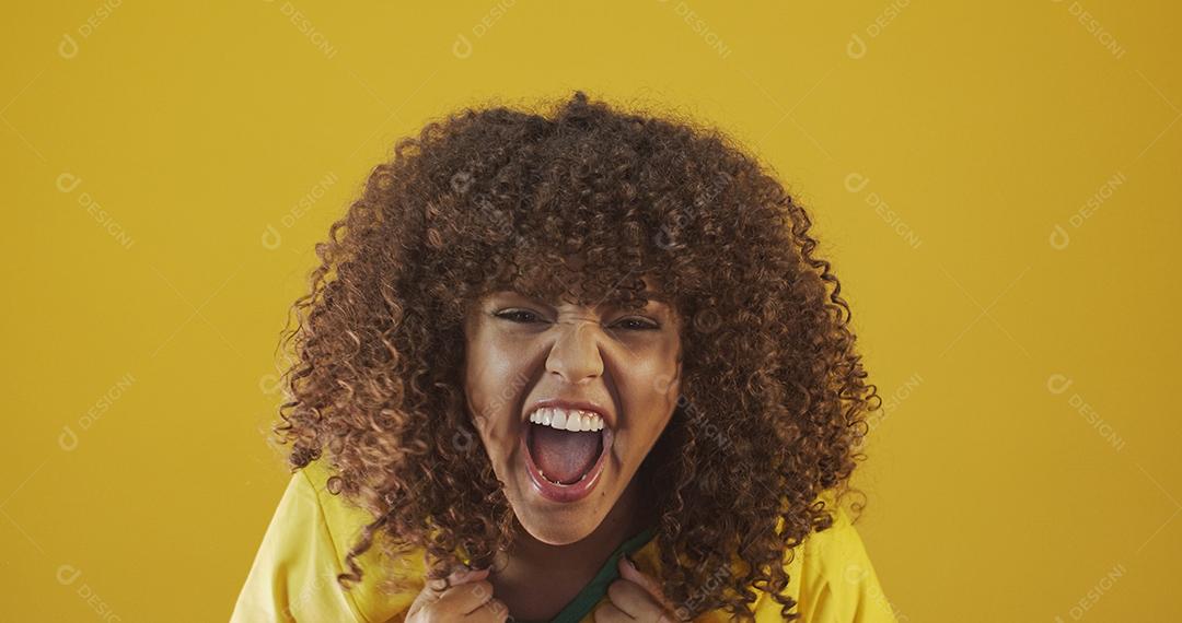 Torcedor do Brasil. Fã de mulher brasileira de cabelo encaracolado comemorando