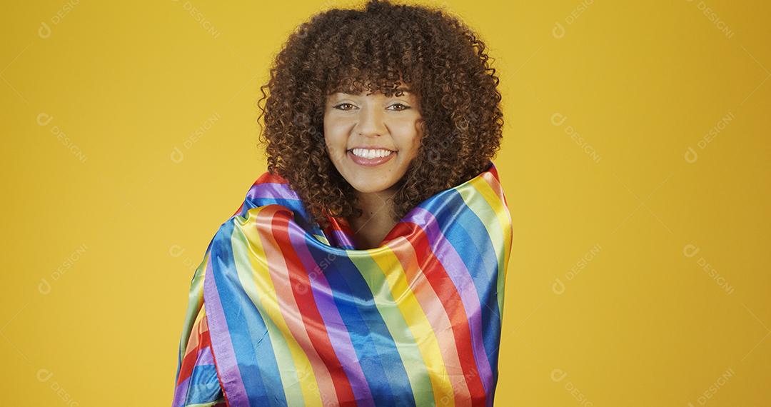 Mulher jovem de cabelo encaracolado cobrindo com a bandeira do orgulho lgbt