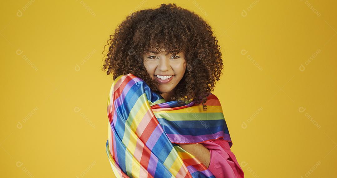 Mulher jovem de cabelo encaracolado cobrindo com bandeira do orgulho lgbt