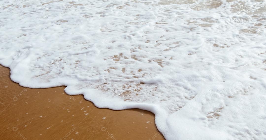 Ondas suaves com espuma do oceano no fundo da praia