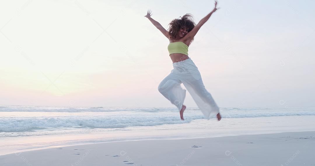 Mulher latina muito feliz na praia. Ela está sorrindo e dançando.