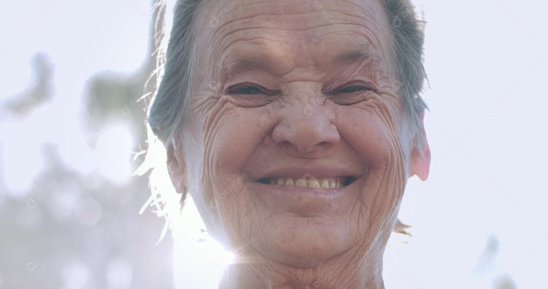 Retrato de uma linda mulher idosa no parque de verão sorrindo.