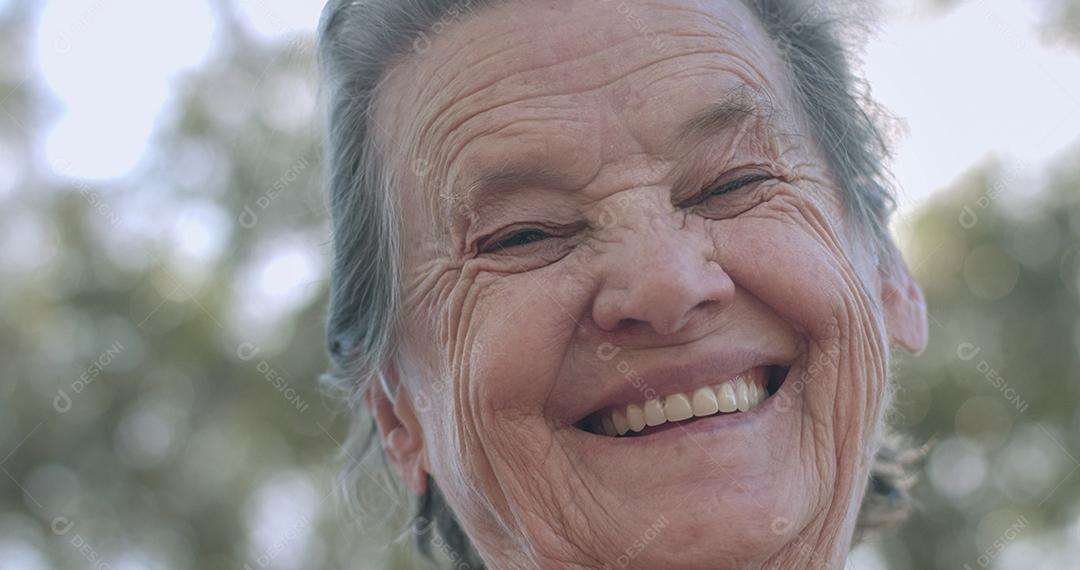 Retrato de uma linda mulher idosa no parque de verão sorrindo.