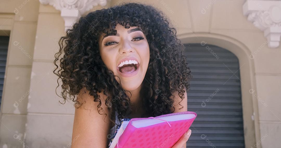 Aluna no campus com livros nos braços