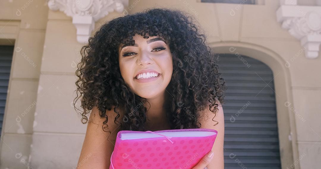 Aluna no campus com livros nos braços