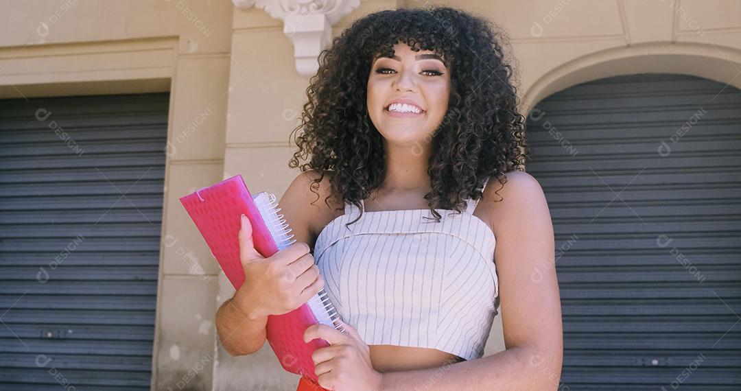 Aluna no campus com livros nos braços