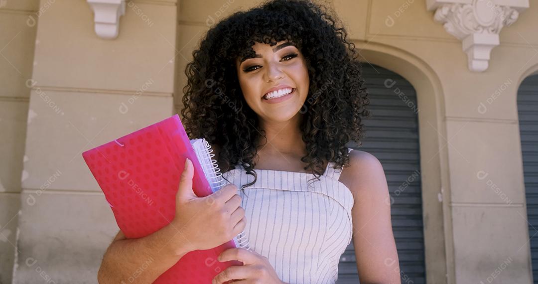 Aluna no campus com livros nos braços