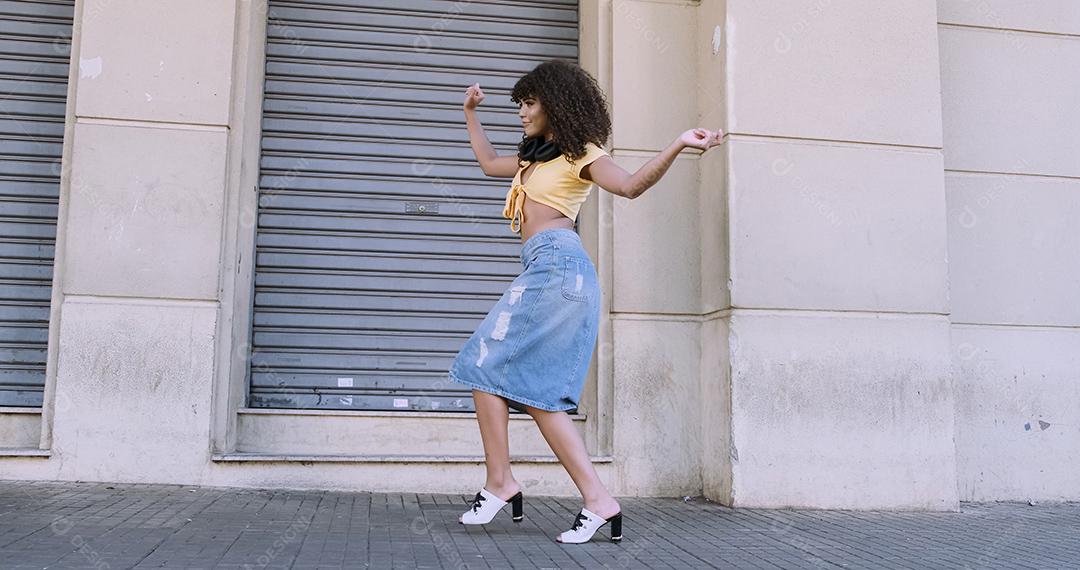 Dançarina de estilo moderno com afro na cabeça dançando na rua