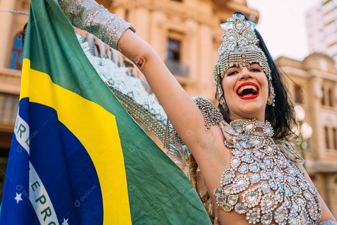 Linda mulher brasileira vestindo fantasia de carnaval colorida e bandeira do Brasil durante o desfile de rua de carnaval na cidade.