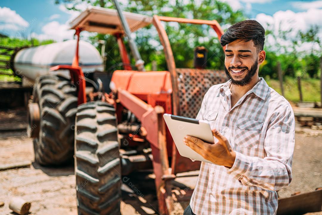 Empresário rural latino verificando o trabalho em tablet digital.