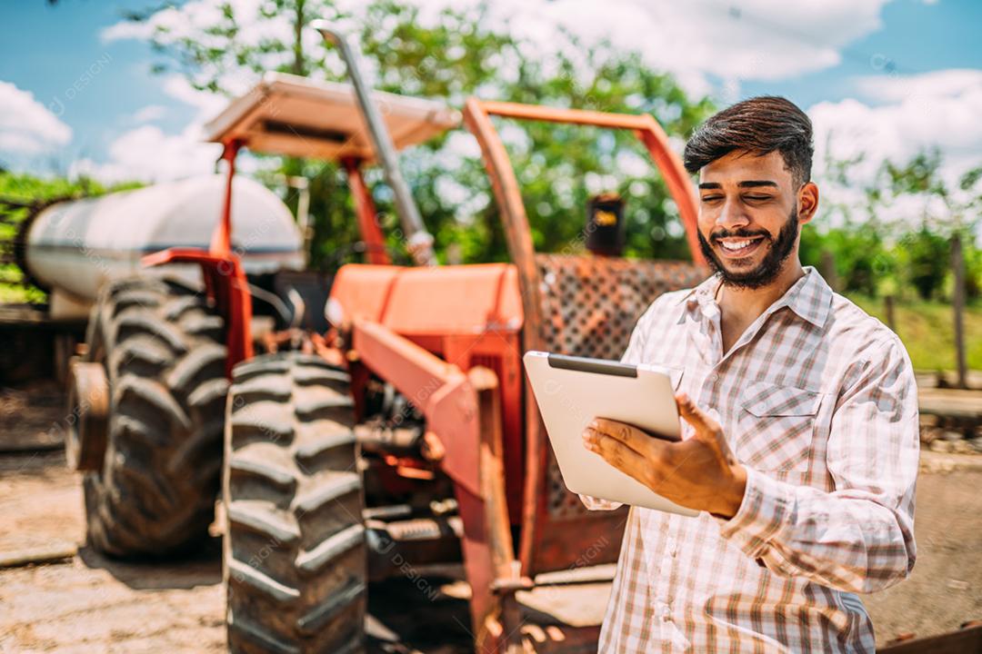 Empresário rural latino verificando o trabalho em tablet digital.