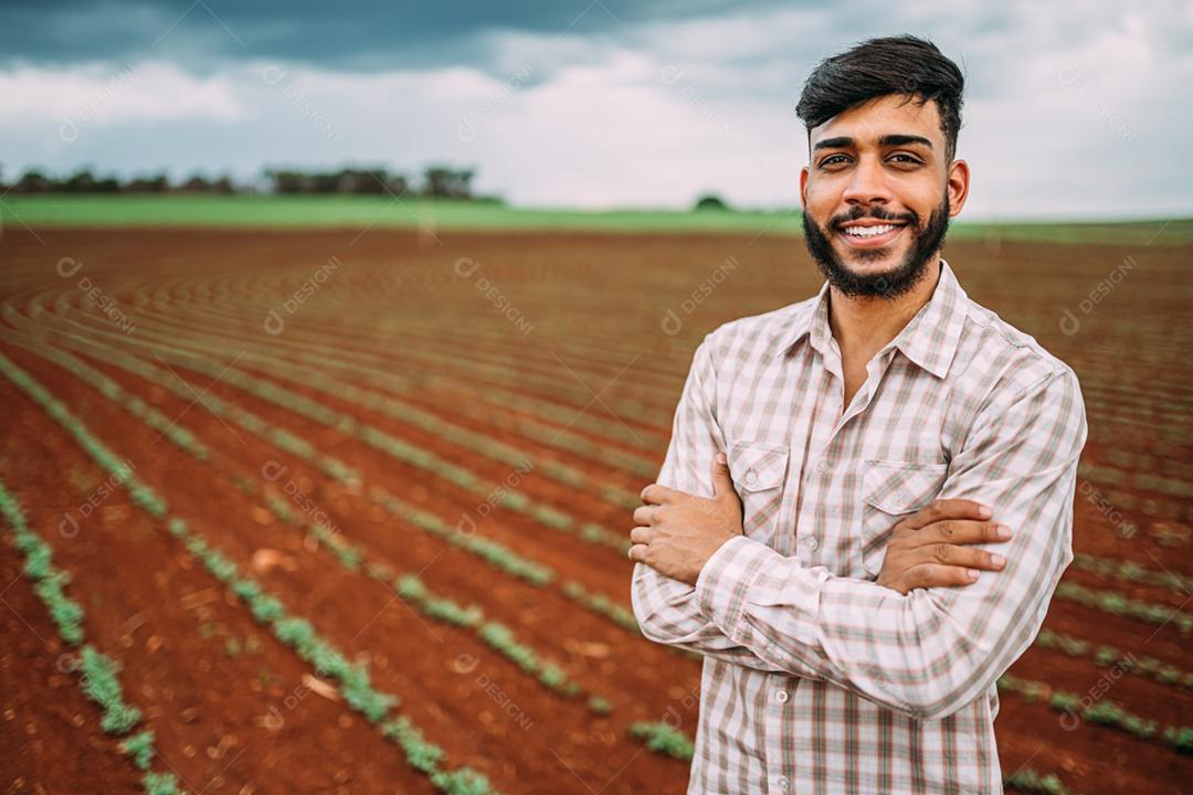 Jovem agricultor latino trabalhando na plantação de amendoim. Agricultor brasileiro olhando para a câmera.