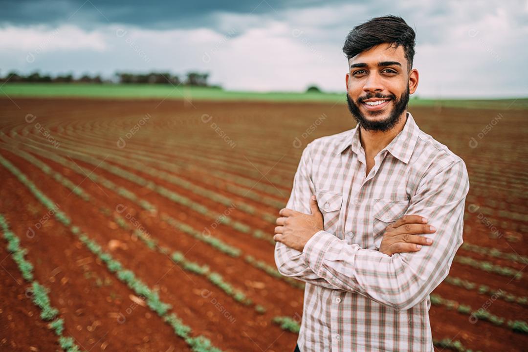 Jovem agricultor latino trabalhando na plantação de amendoim. Agricultor brasileiro olhando para a câmera.