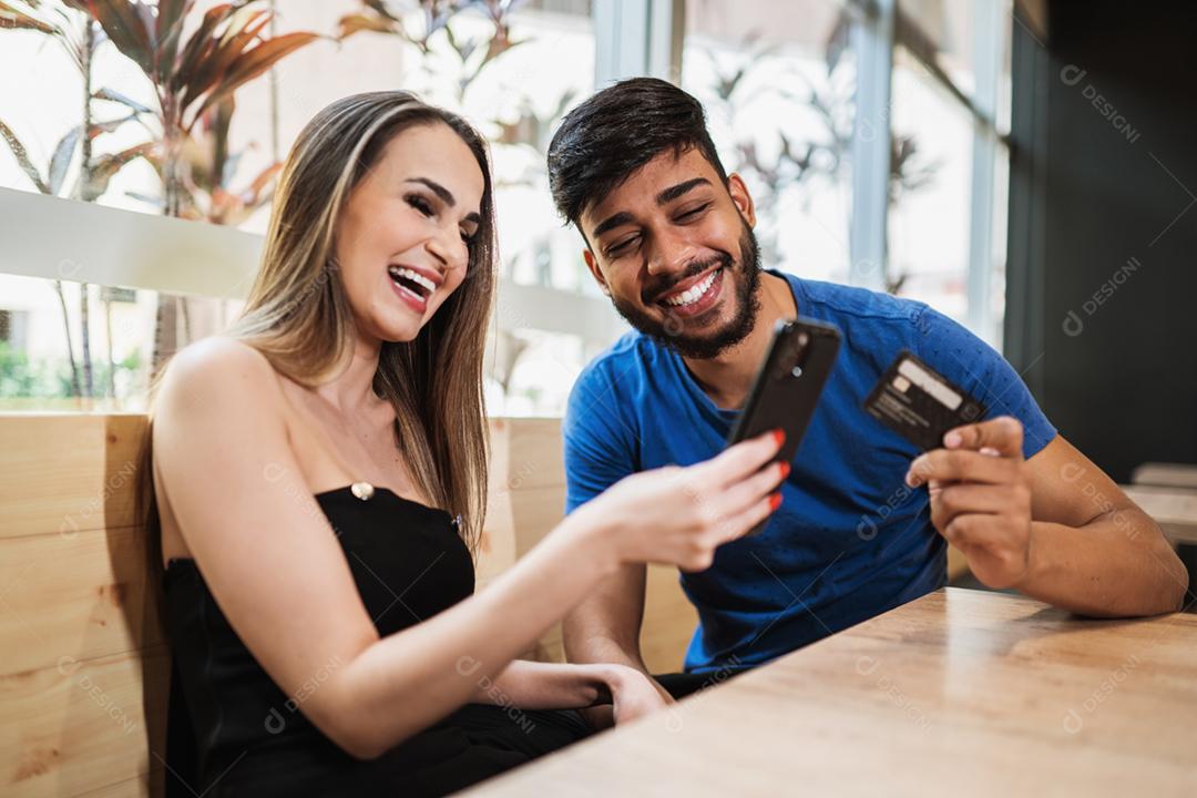 Banco on-line jovem casal usando smartphone fazendo compras on-line com cartão de crédito na varanda