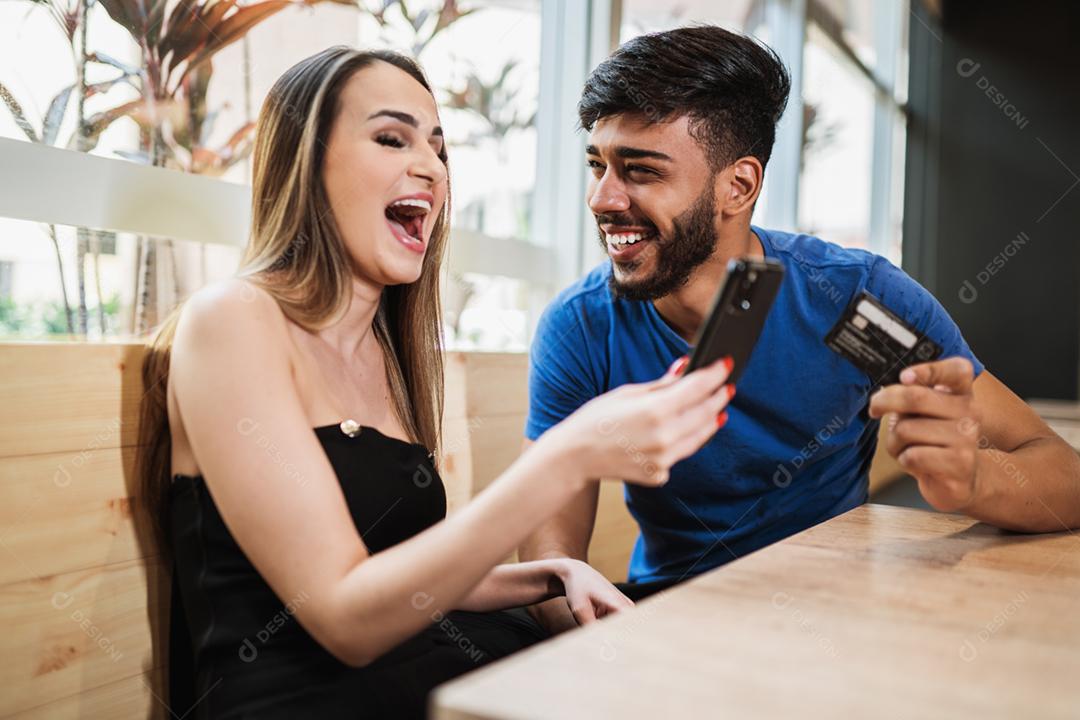 Banco on-line jovem casal usando smartphone fazendo compras on-line com cartão de crédito na varanda