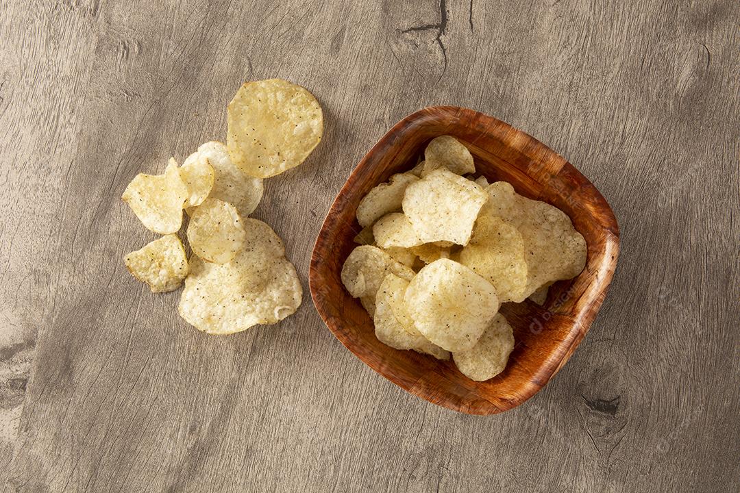 Batatas fritas em uma tigela de madeira sobre fundo de madeira
