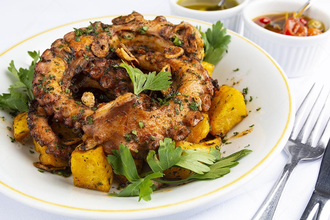 Polvo grelhado e batatas sobre um prato branco em um espanhol