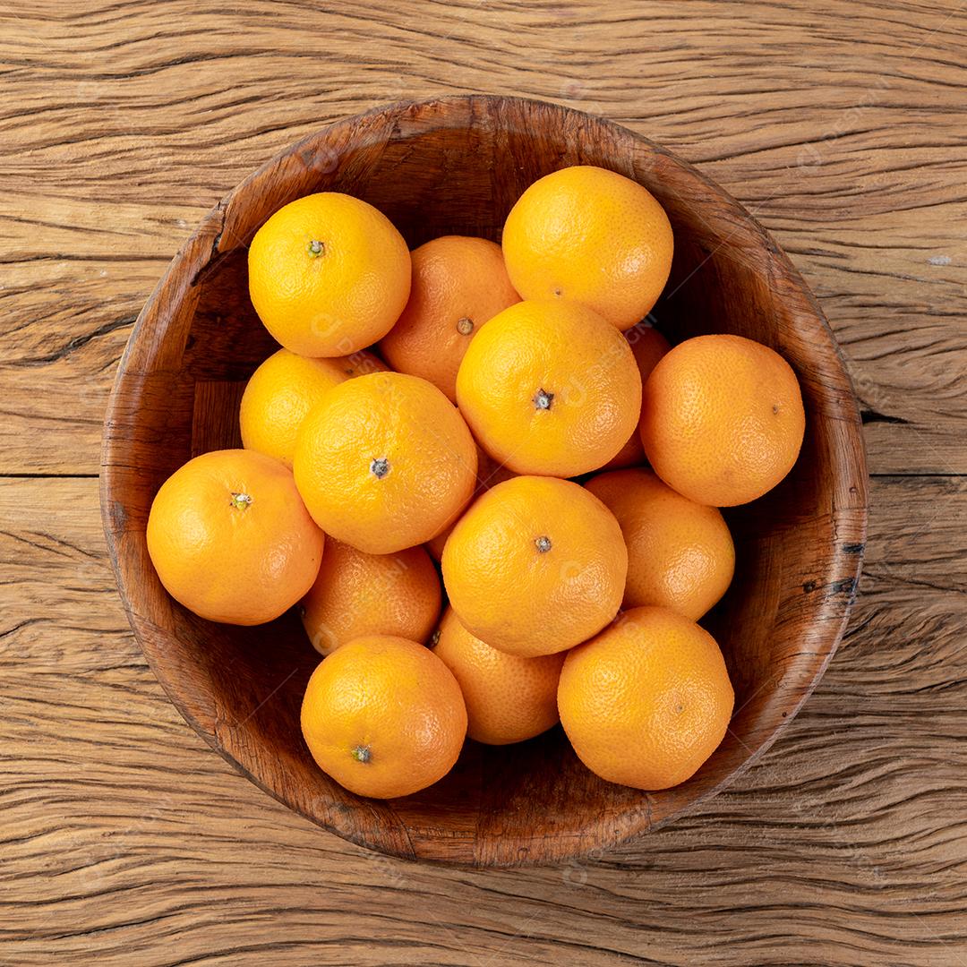 Mini tangerinas em uma tigela sobre a mesa de madeira