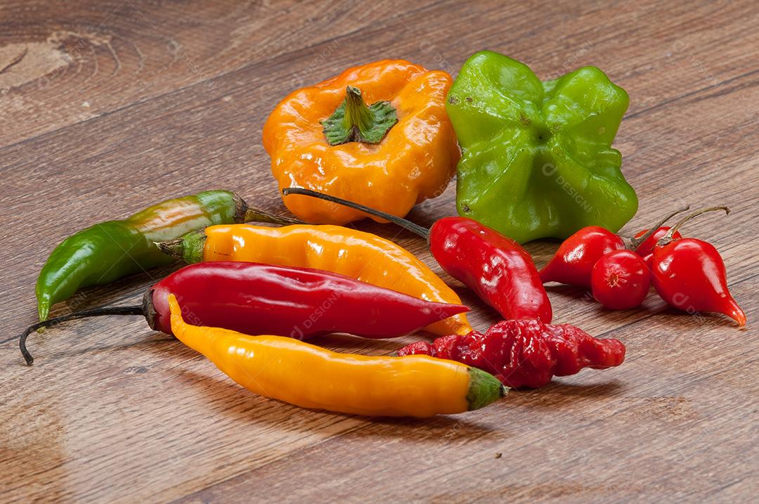 Pimentas variadas sobre mesa de madeira. Pano de fundo alimentar