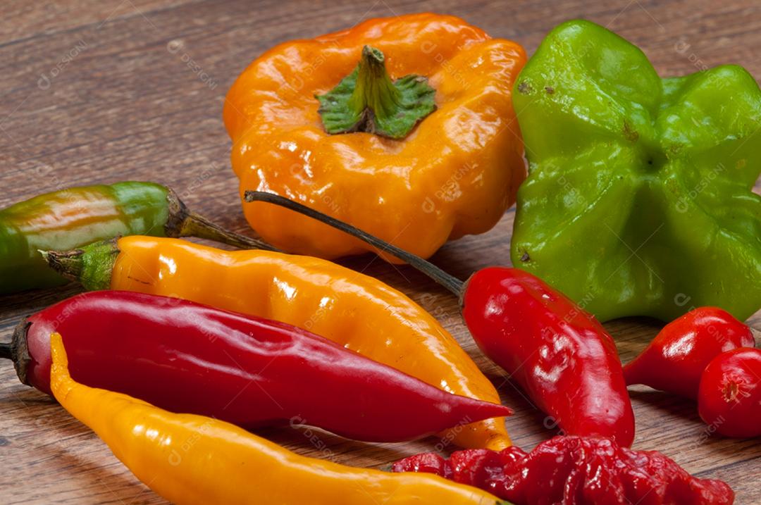 Pimentas variadas sobre mesa de madeira. Pano de fundo alimentar