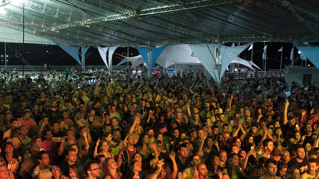 Várias pessoas á noite reunidas em um lugar, se divertindo. Pessoas.