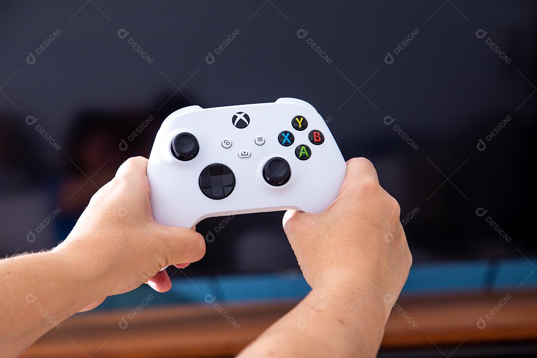 São Paulo, Brasil - 03, 2022: Garota jogando o novo console xbox Series S. Com uma televisão em segundo plano.