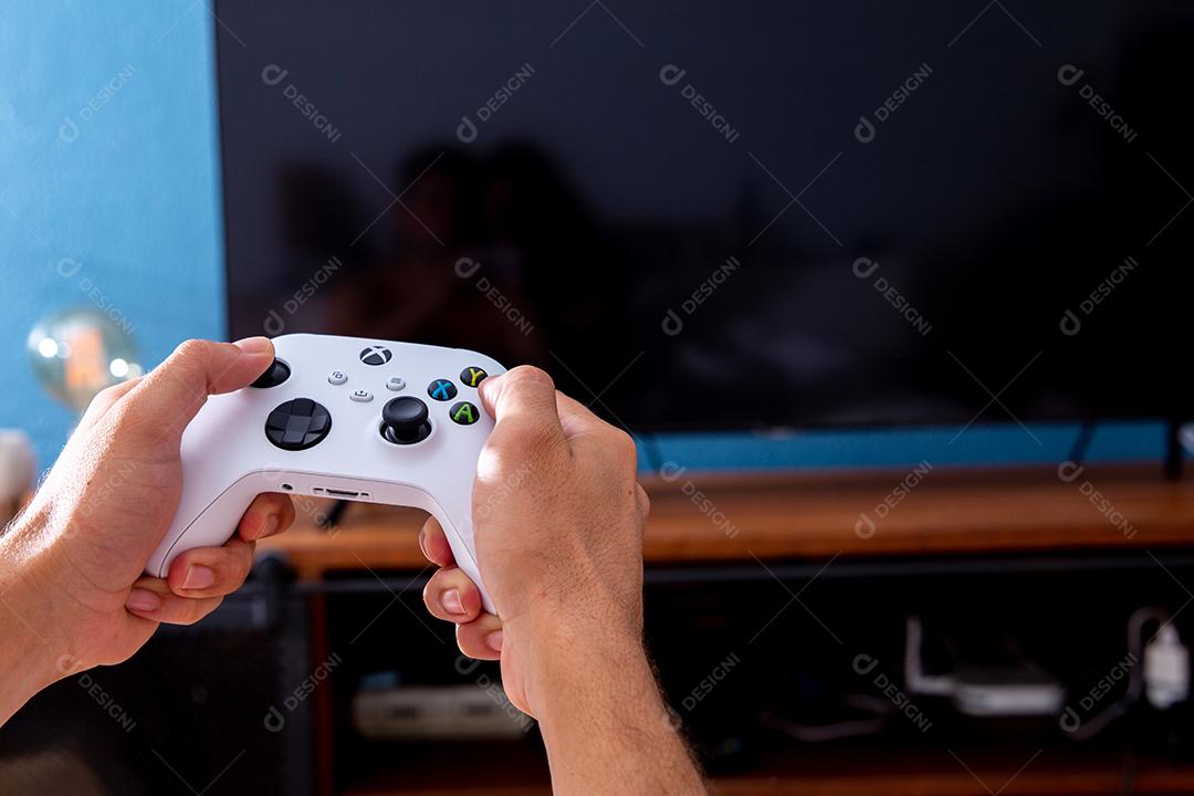 São Paulo, Brasil - 03, 2022: Homem jogando o novo console xbox Series S. Com uma televisão em segundo plano.