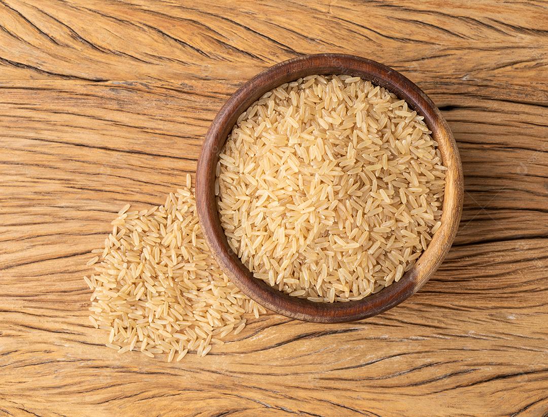 Arroz integral integral cru em uma tigela sobre mesa de madeira