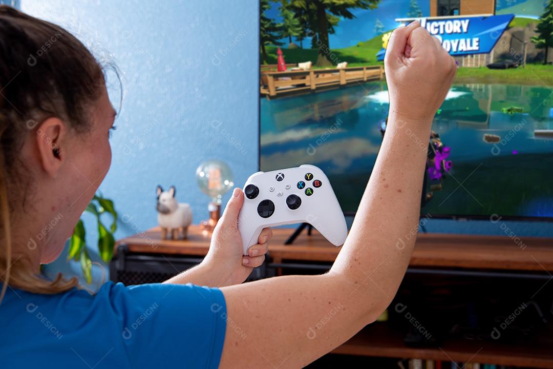 São Paulo, Brasil - 03, 2022: Garota jogando o novo console xbox Series S. Com uma televisão em segundo plano.