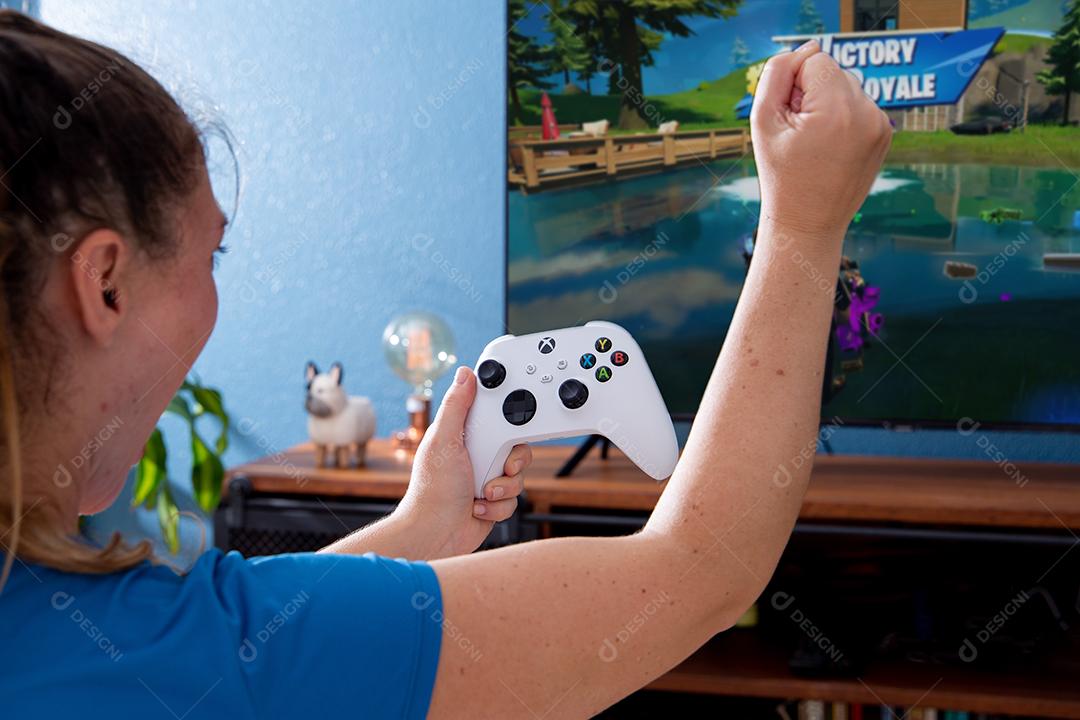 São Paulo, Brasil - 03, 2022: Garota jogando o novo console xbox Series S. Com uma televisão em segundo plano.