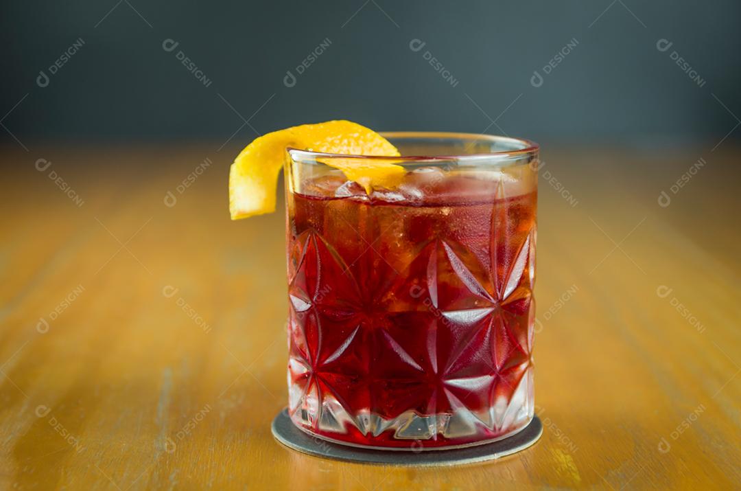 Cocktail Negroni clássico em um copo retrô com gelo e casca de laranja em um fundo preto