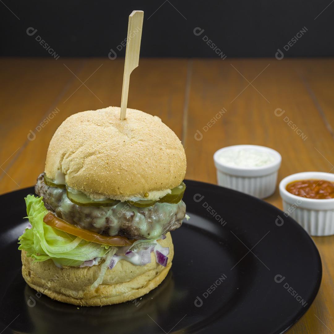 Close-up de hambúrguer caseiro saboroso na mesa de madeira e fundo preto