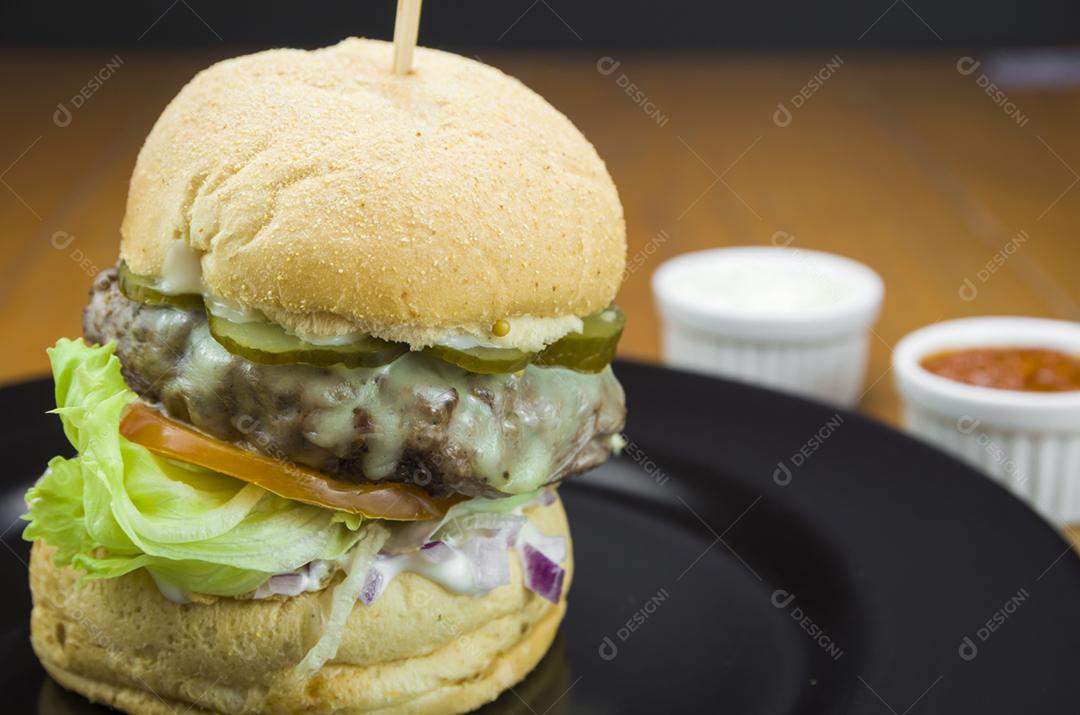 Close-up de hambúrguer caseiro saboroso na mesa de madeira e fundo preto