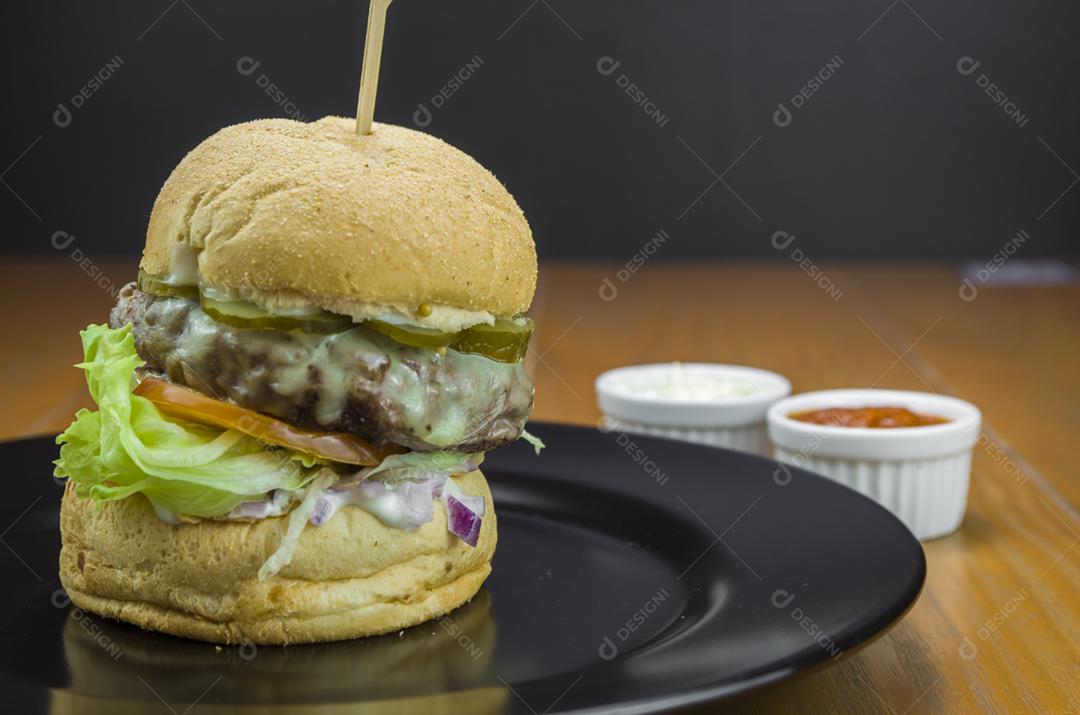 Close-up de hambúrguer caseiro saboroso na mesa de madeira e fundo preto