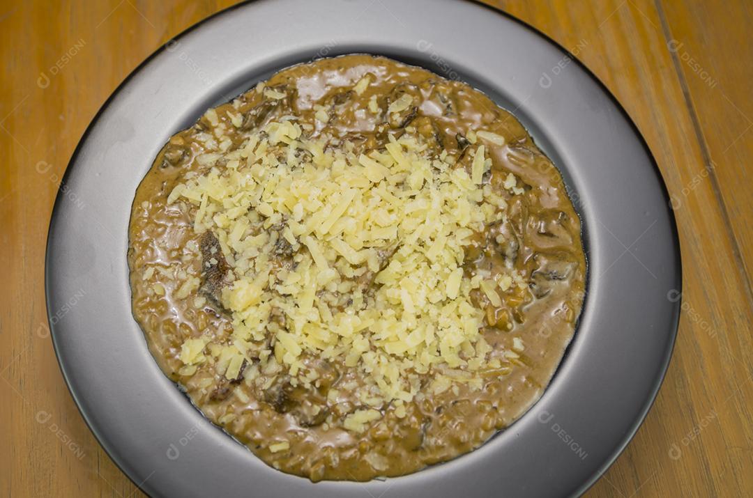 Risoto de funghi saboroso com close-up de carne e queijo.