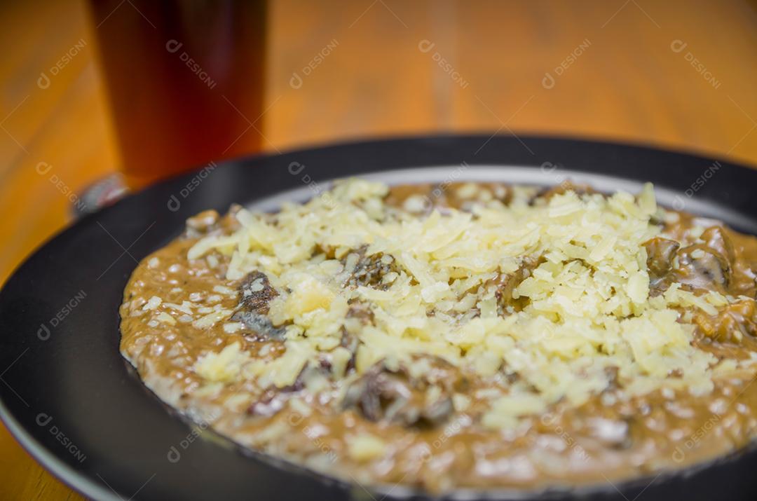 Risoto de funghi saboroso com close-up de carne e queijo.