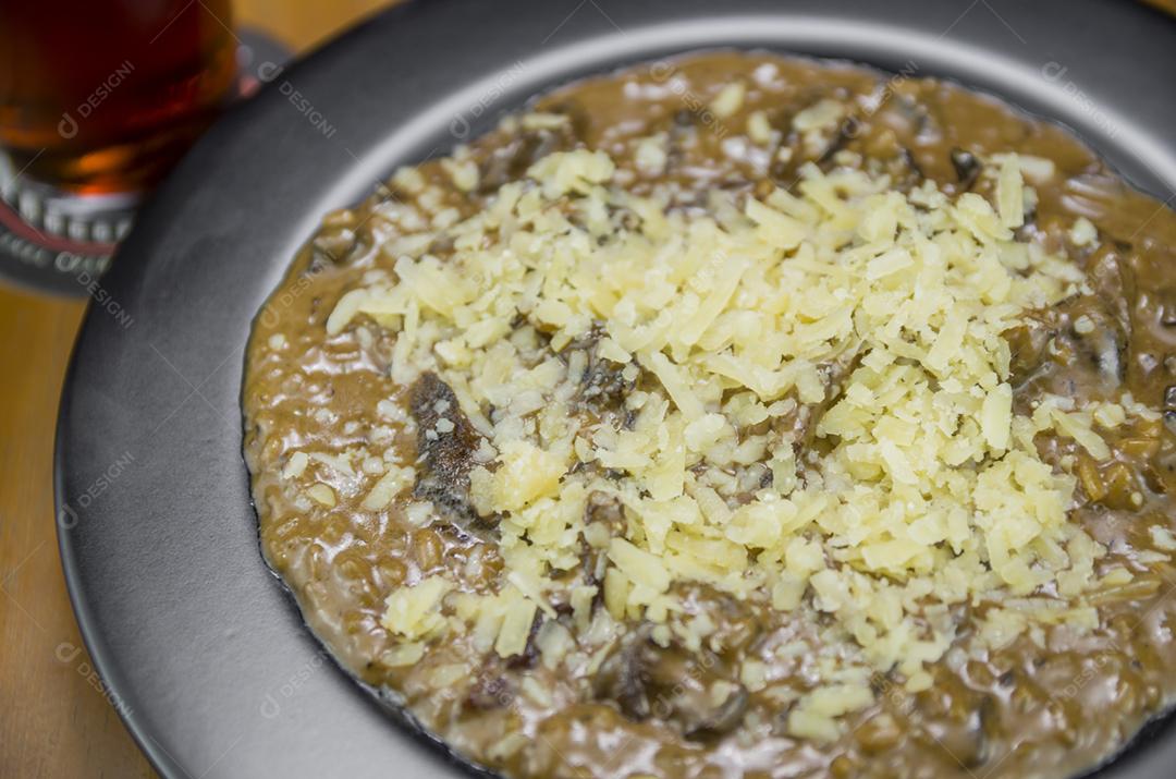 Risoto de funghi saboroso com close-up de carne e queijo.