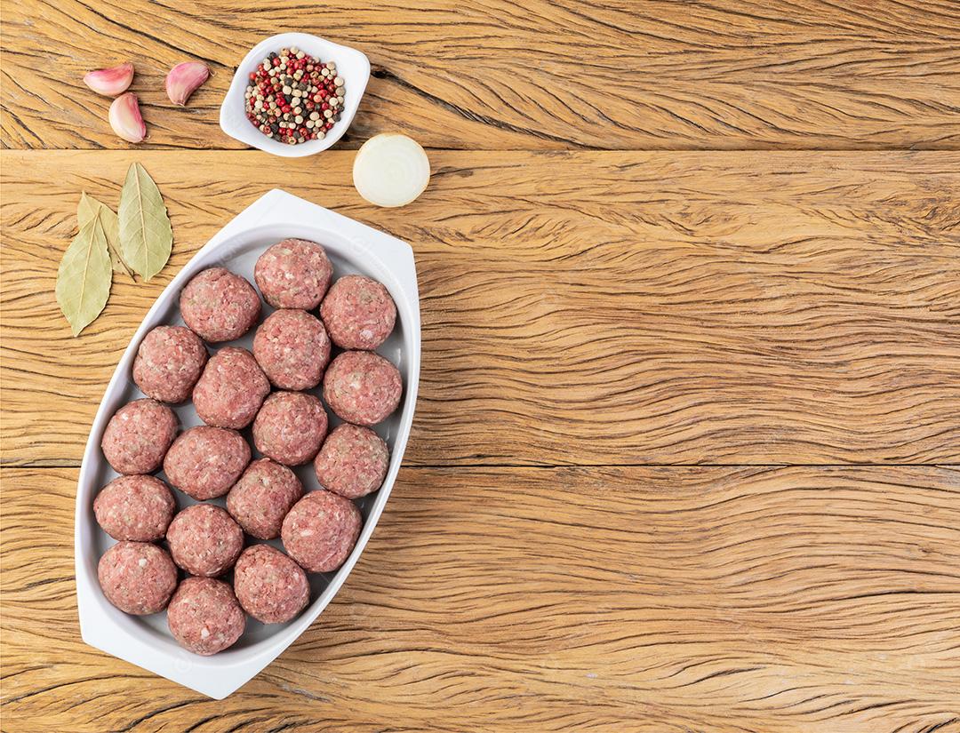 Bolas de carne crua em um prato branco com temperos
