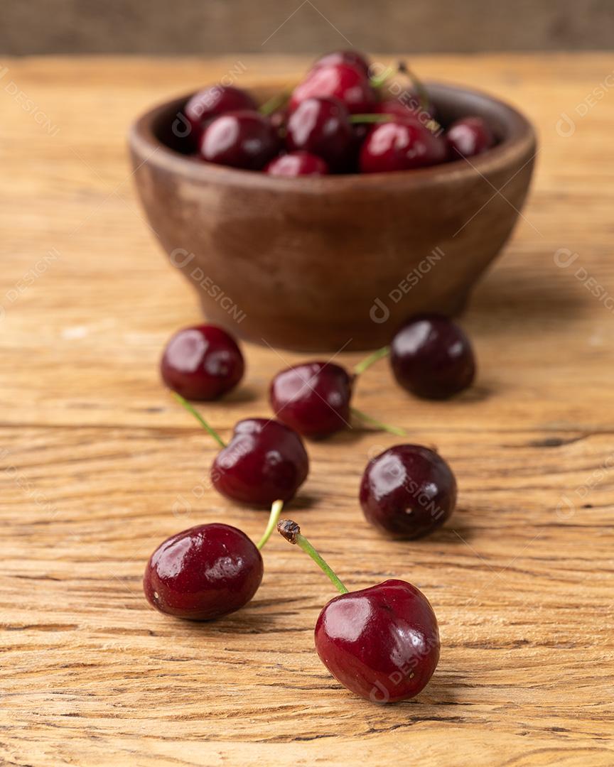 Cerejas vermelhas em uma tigela sobre a mesa de madeira