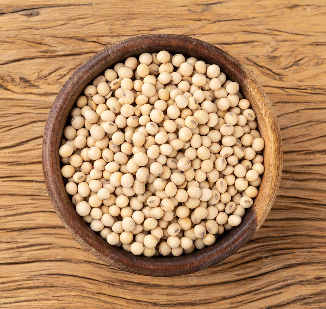 Grãos de soja crus em uma tigela sobre a mesa de madeira