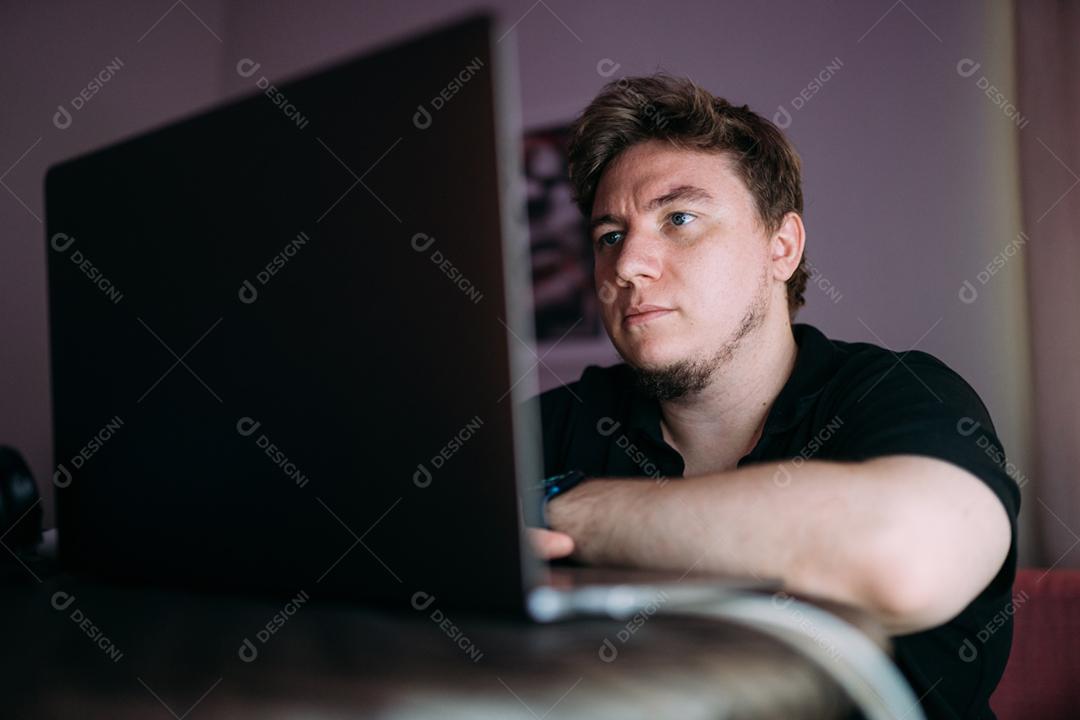 Homem concentrado sentado em casa usando o computador portátil