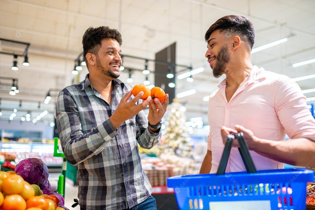Casal gay latino-americano colhendo tomates no supermercado