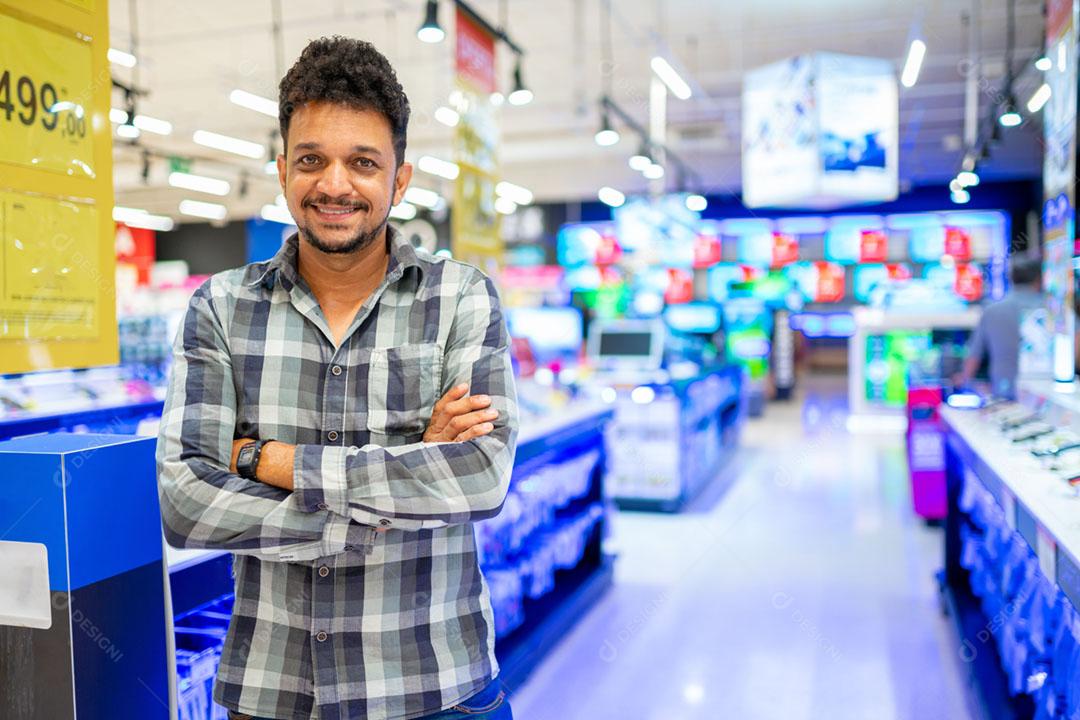 Latino-americano no supermercado. Homem sorridente com os braços cruzados e olhando para a câmera