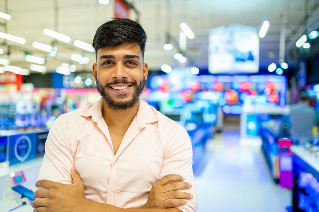 Latino-americano no supermercado. Homem sorridente com os braços cruzados e olhando para a câmera