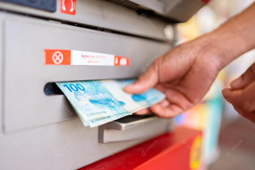 A mão do homem retirando dinheiro do caixa eletrônico