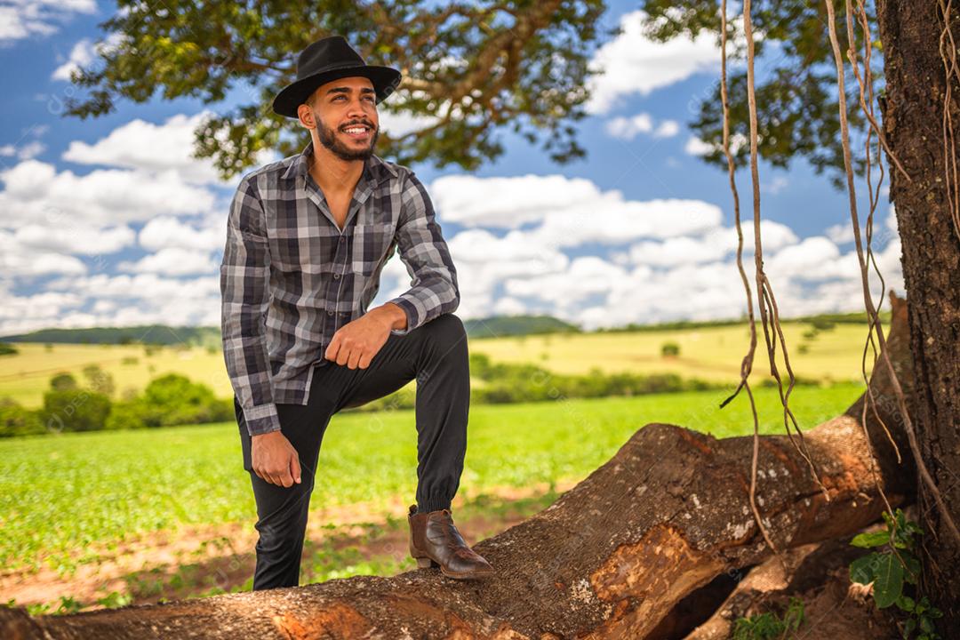 Agricultor latino-americano trabalhando na plantação. Jovem olhando para o horizonte à direita