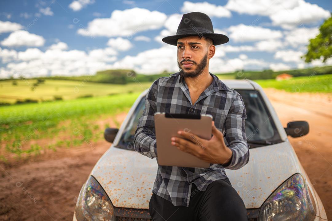 Agricultor latino-americano analisando estatísticas em tablet digital